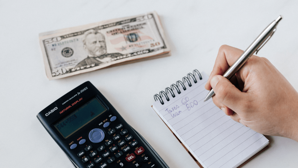 A person using calculator and pen to write on paper