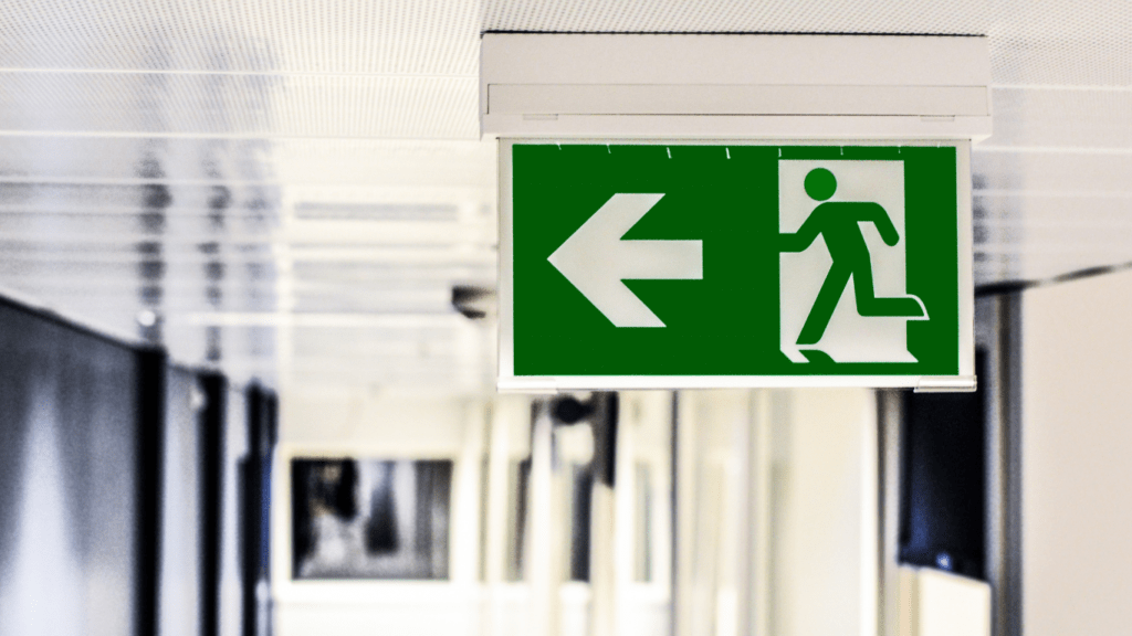 a green emergency exit sign on a wall in a hallway