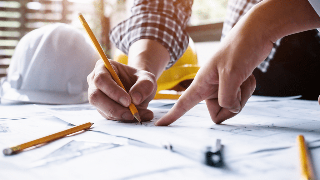 two people working on construction plans with pencils and hard hats