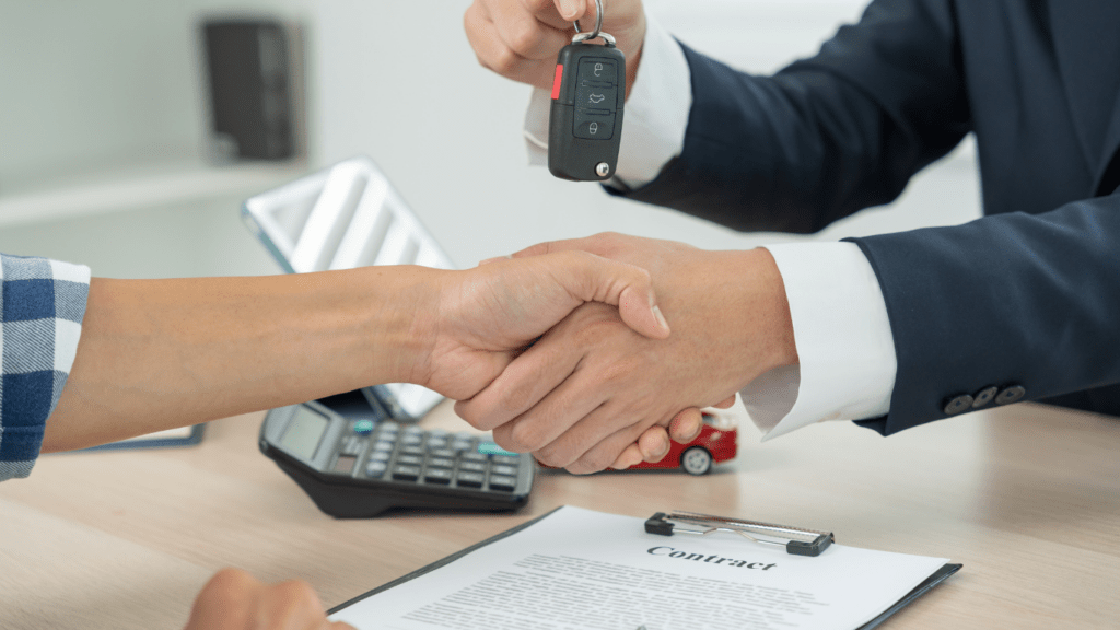 two people shaking hands over a desk with a key