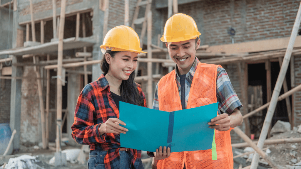 Two people in hard hats standing in front of a construction site