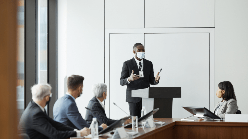 a person in a suit is giving a speech in front of a group of people