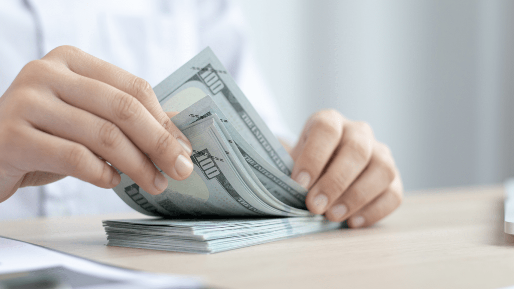 a person is counting money in front of a laptop