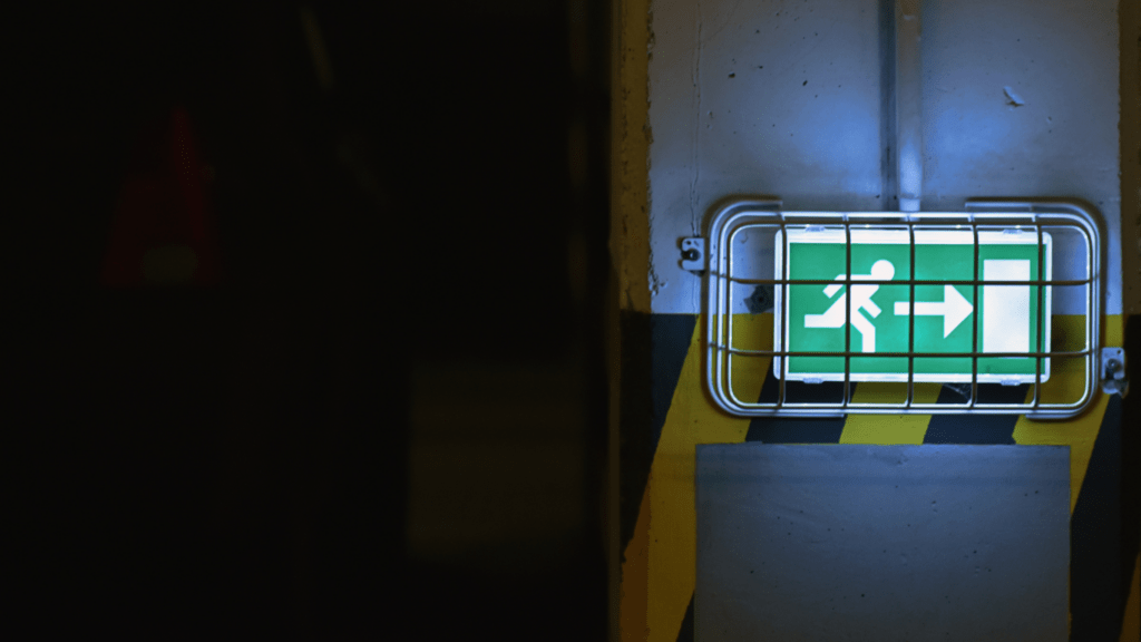 a green emergency exit sign on a wall in a hallway