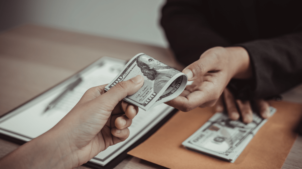 a person is counting money in front of a laptop