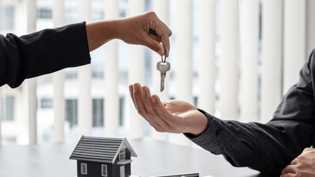 two people shaking hands over a desk with a key