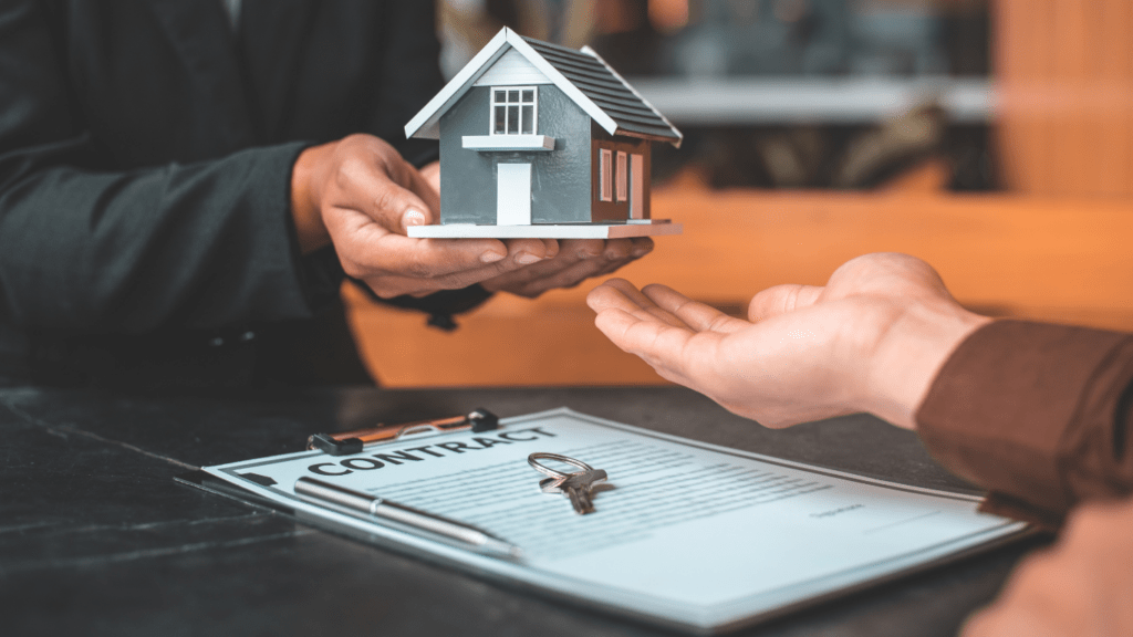 two people sitting at a table with a house model in front of them