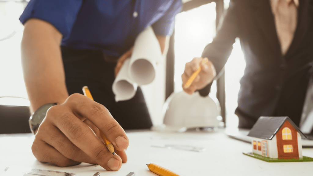 two people working on construction plans with pencils and hard hats